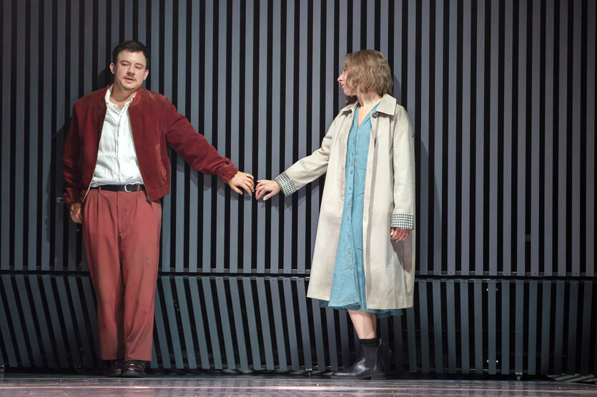 Die beiden Schauspieler Paul Zichner und Kathleen Morgeneyer fassen sich vor einer Mauer an den Händen