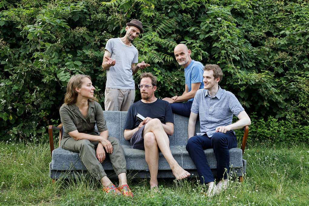 Fünf Menschen auf und an einem Sofa im Grünen