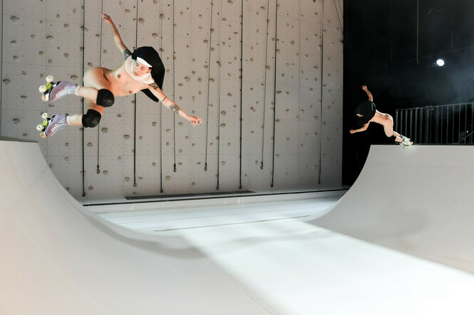 Schauspielerinnen auf einer Bühne mit Rollschuhen in einer Halfpipe.