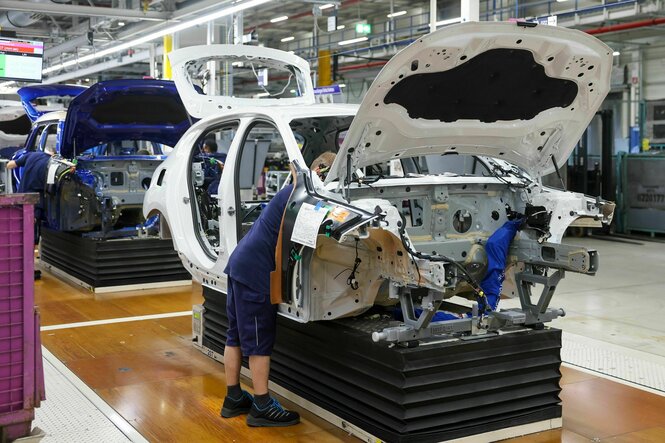 Ein Mitarbeiter arbeitet an der Karosserie eines BMW in der Montagehalle