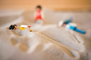 Eine Playmobilfigur versinkt im Sand