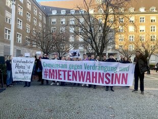Die Unterstützer:innen der Bewohner:innen der Habersaathstraße versammeln sich hinter einem Demobanner vor dem Rathaus Tiergarten.