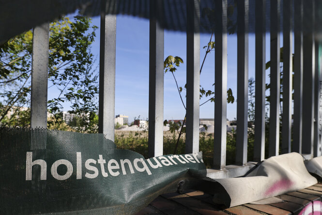 Blick durch Zaunstäbe auf das Holstenareal