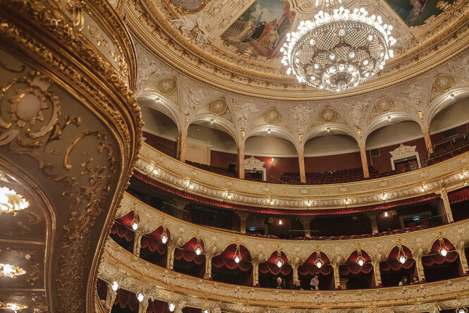 Ein prächtiger Zuschauerraum einer Oper mit einem Kronleuchter, Gold und Samt