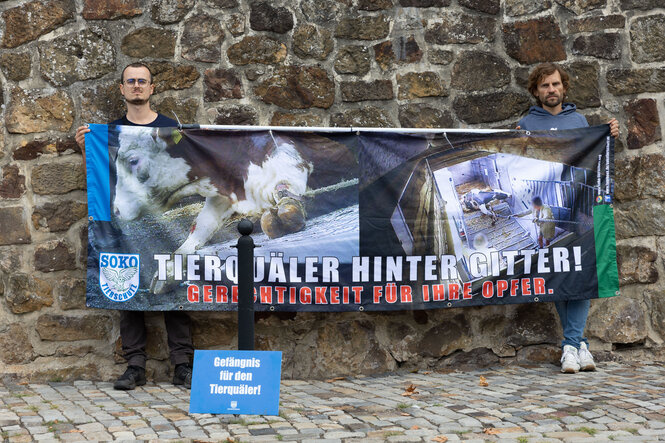 Zwei Tierrechts-Aktivisten halten ein Banner mit Aufnahmen aus dem Schlachthof