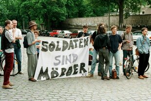 Protestierende halten ein Banner, auf dem steht: Soldaten sind Mörder