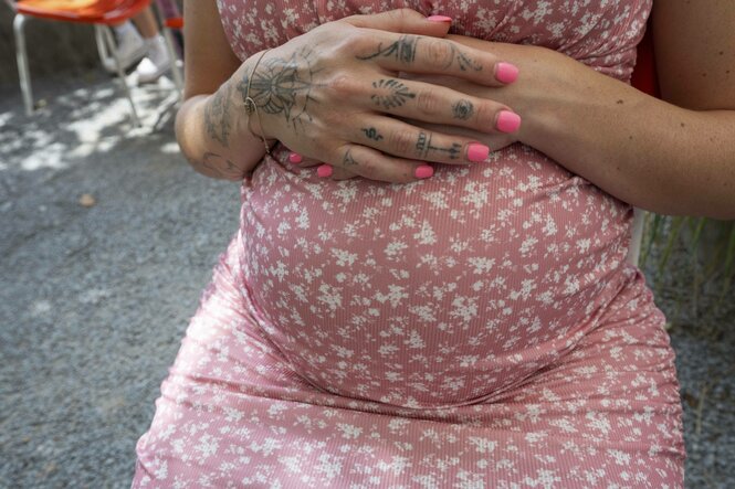 Eine schwangere Frau hält die Hände über ihrem Bauch zusammen