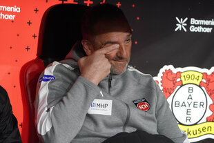 Ein Mann in Sport-Outfit sitzt auf der Trainerbank und reibt sich verzweifelt die Augen