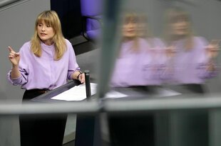 Clara Bünger spricht am Rednerpult und hebt den Zeigefinger