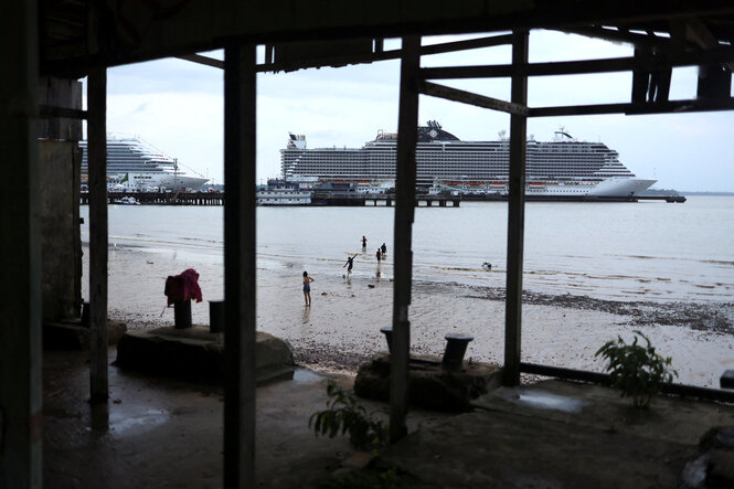 Menschen beobachten vom Strand die Kreuzfahrtschiffe aim Hafen