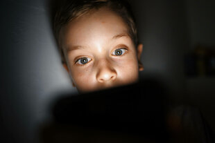 Eine junge Person schaut in ein Smartphone.