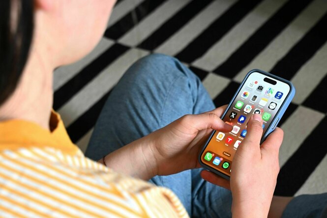 Eine Jugendliche sitzt auf dem Boden und nutzt ein Smartphone