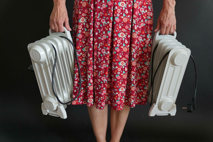 Eine Frau im roten Kleid hält zwei kleine Heizkörper in den Händen