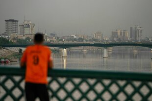 Ein Mann lehnt in einem roten T-Shirt an einer Brücke über den Tigris in Bagdad