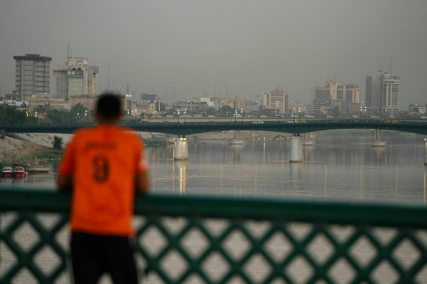 Ein Mann lehnt in einem roten T-Shirt an einer Brücke über den Tigris in Bagdad