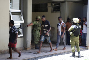 Gefangene werden von Uniformierten zum Gericht geleitet.