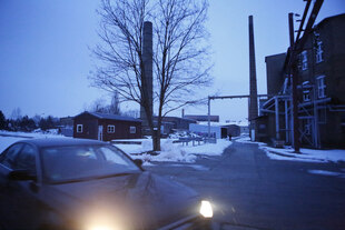 Ein Auto fährt zur blauen Stunde am Telux-Gelände im verschneiten Weißwasser vorbei