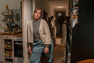 Ein Frau lehnt sich an einen Türpfosten in ihrer Wohnung