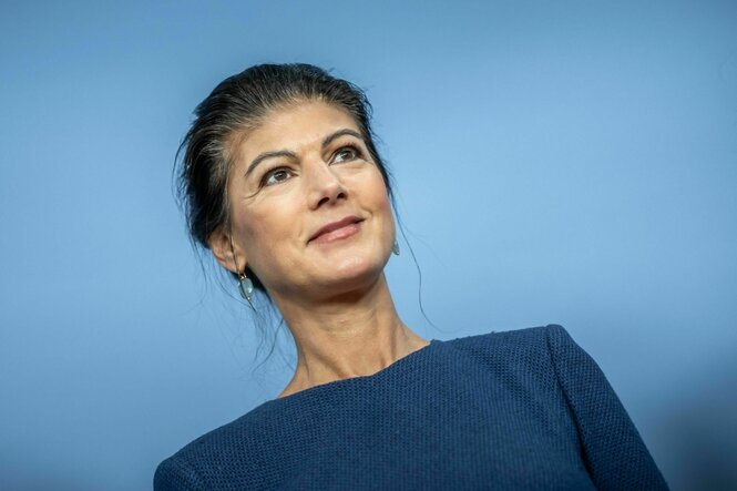 Sahra Wagenknecht schaut vor blauem Hintergrund nach rechts oben