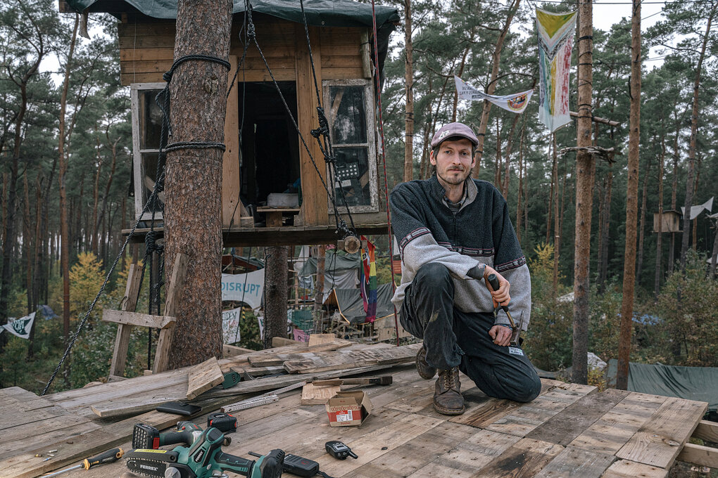 Ein Mann sitzt vor einem Baumhaus
