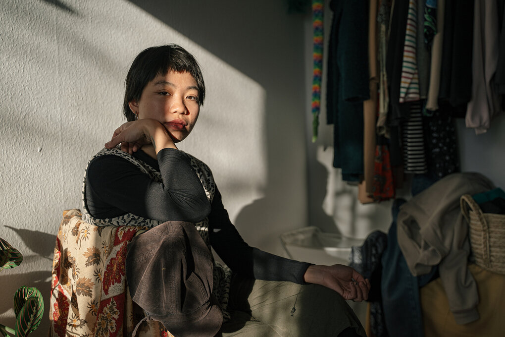 Eine Frau sitzt in ihrer sonnendurchfluteten Wohnung