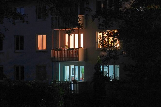 Beleuchtete Fenster von Wohnhäusern in der Dunkelheit.