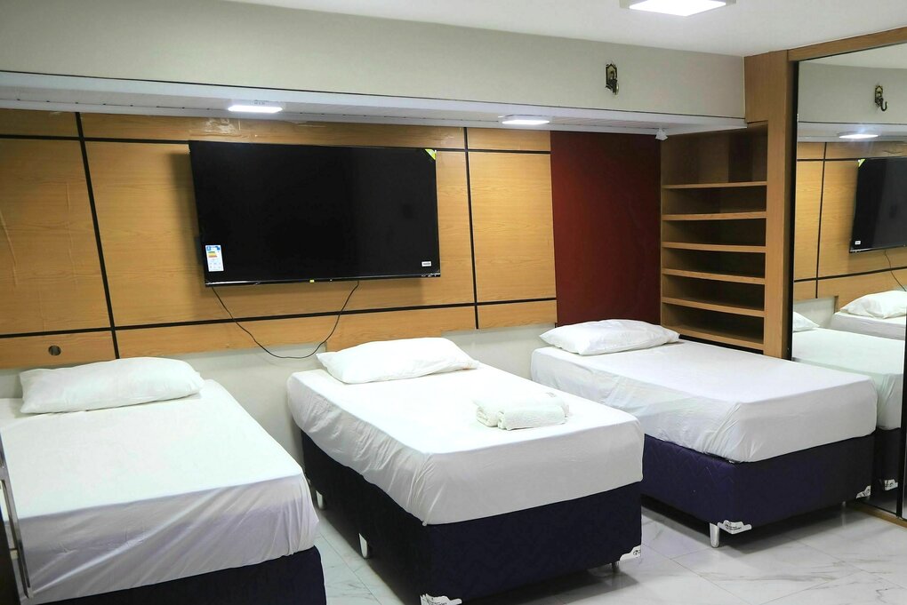 Hotelzimmer mit drei einzelnen Betten, die mit weisser Bettwäsche bezogen sind