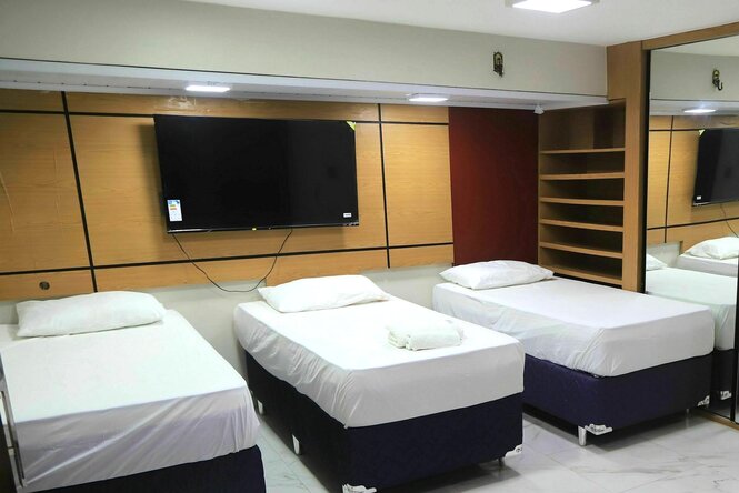 Hotelzimmer mit drei einzelnen Betten, die mit weisser Bettwäsche bezogen sind