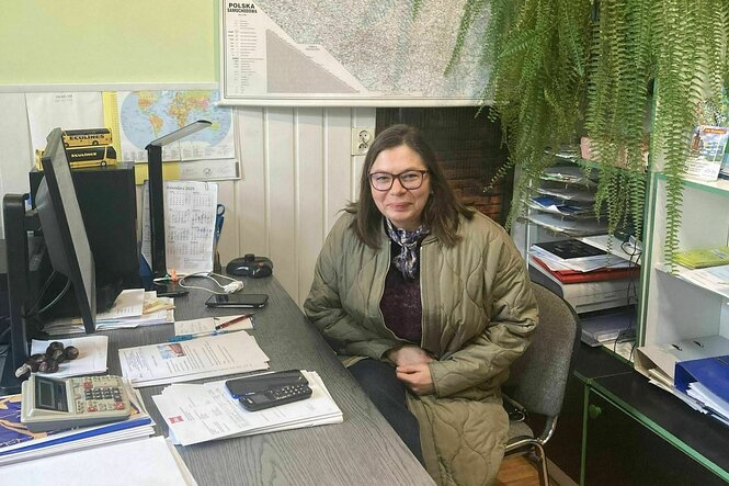 Malgorzata Walukiewicz sitzt in ihrem Büro mit großer Grünpflanze im Hintergrund