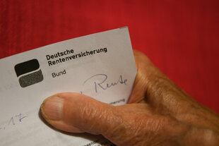 Eine ältere Frau hält ihren Rentenbescheid in der Hand.