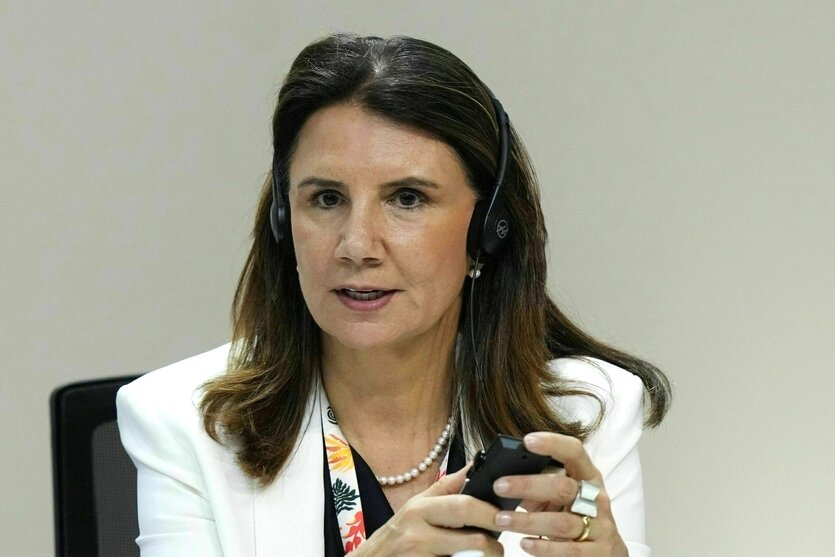 Porträt von Ana Toni, mit Kopfhörer und dem Smartphone in der Hand. Sie hat lange, dunkle Haare, trägt ein helles Jacket und Perlenketter