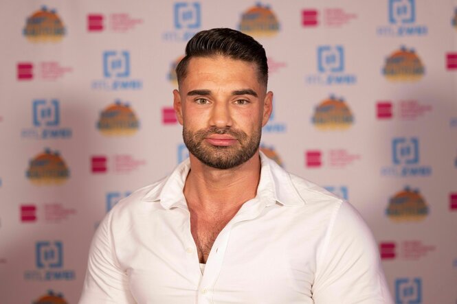 Alexander Petrovic vor einer Pressewand, Hemd halb offen