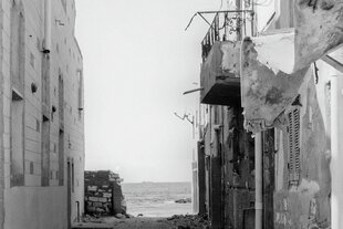 Blick durch eine Gasse zwischen Häusern aufs Meer