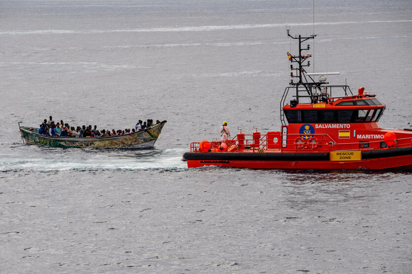 Ein Seenotrettungsboot begleitet ein kleineres Boot mit vielen Menschen an Bord.