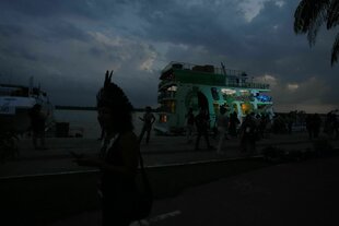 Abendstimmung, eine Fähre am Kaimit einer Person mit Kopfschmuck bereits von der Dunkelheit umhüllt