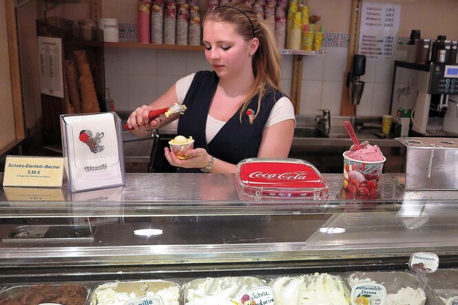 Eine Person hinter der theke eines Eisladens.