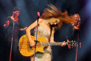 Eine blonde Frau mit brauner Gitarre auf einer Bühne