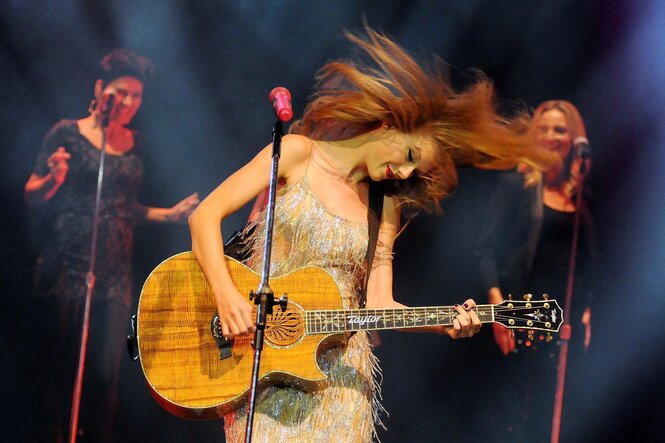 Eine blonde Frau mit brauner Gitarre auf einer Bühne
