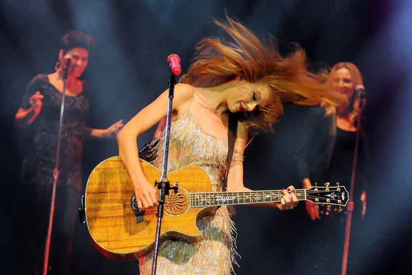 Eine blonde Frau mit brauner Gitarre auf einer Bühne