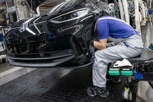 Ein Arbeiter steckt seinen Kopf in einer Autofabrik in einen Radkasten.