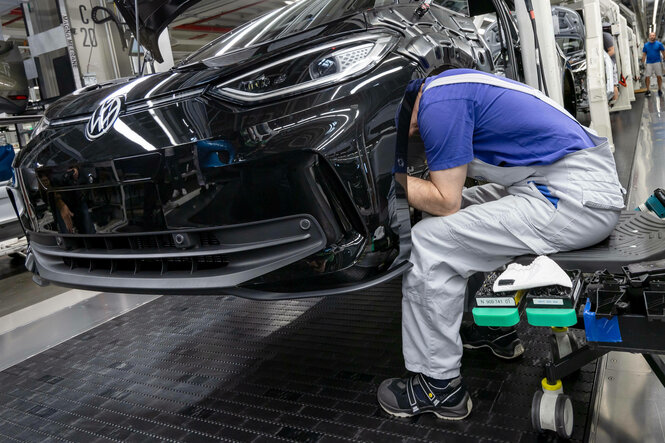 Ein Arbeiter steckt seinen Kopf in einer Autofabrik in einen Radkasten.