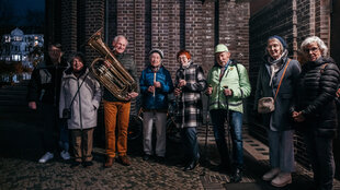 Eine Menschengruppe vor einer Kirchenmauer