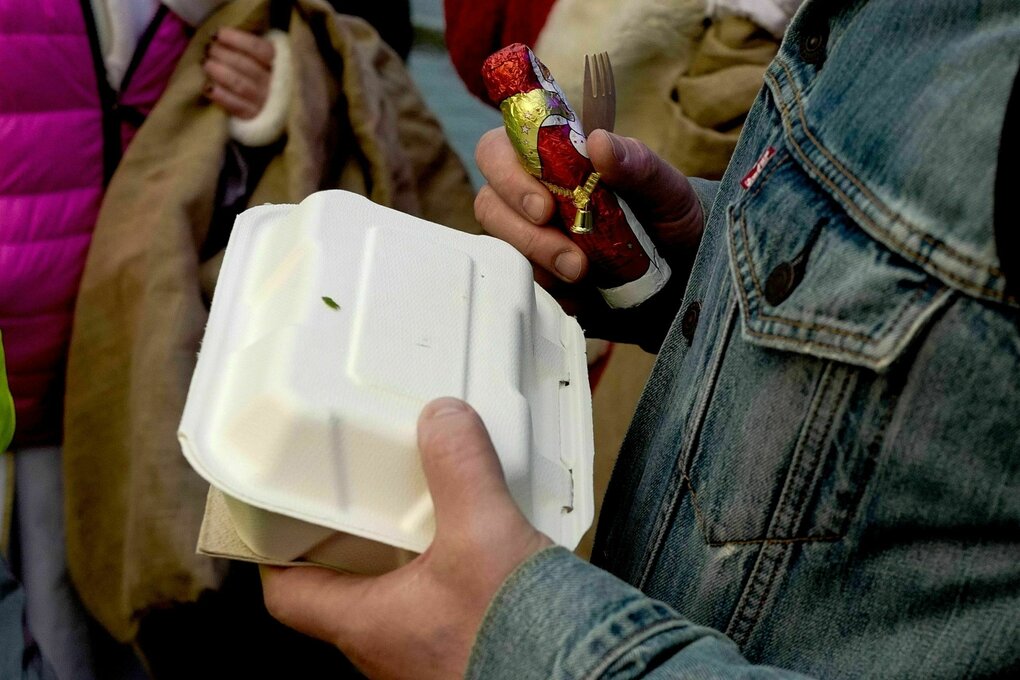 Eine Person hält eine Essensbox und einen Schockoladen-Nikolaus in den Händen