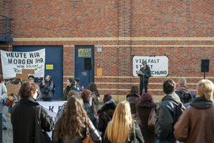 Auf dem Campus Wilhelminenhof der Hochschule für Technik und Wirtschaft haben sich Studierende vor einer Bühne und Lautsprecheranlage versammelt, um gegen die geplante Streichung mehrerer Studiengänge zu protestieren.