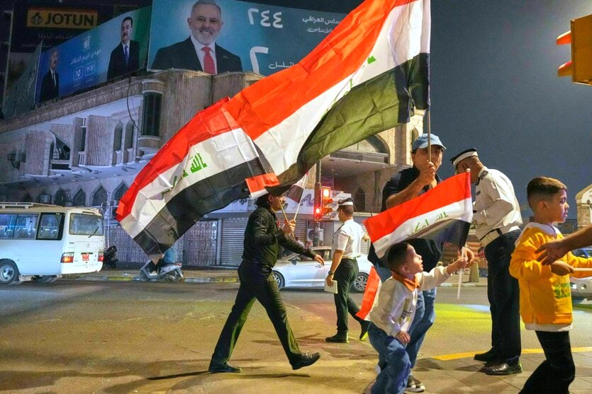 Menschen gehen mit irakischen Flaggen über den Tahrir-Platz in Bagdad
