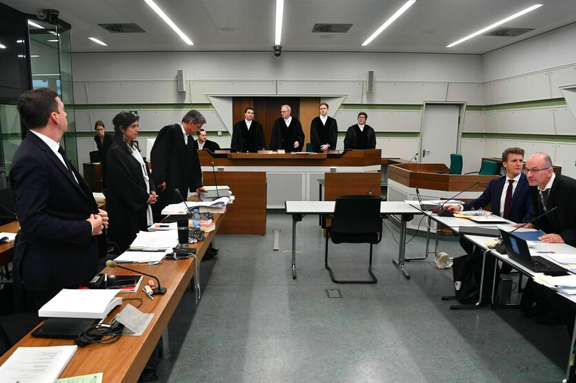 Blick in den Verhandlungsraum, Männer und Frauen in schwarzen Roben stehen vor ihren Tischen