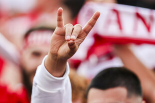 Ein junger Mann zeigt während eines Fußballspiels den Wolfsgruß