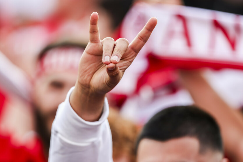 Ein junger Mann zeigt während eines Fußballspiels den Wolfsgruß