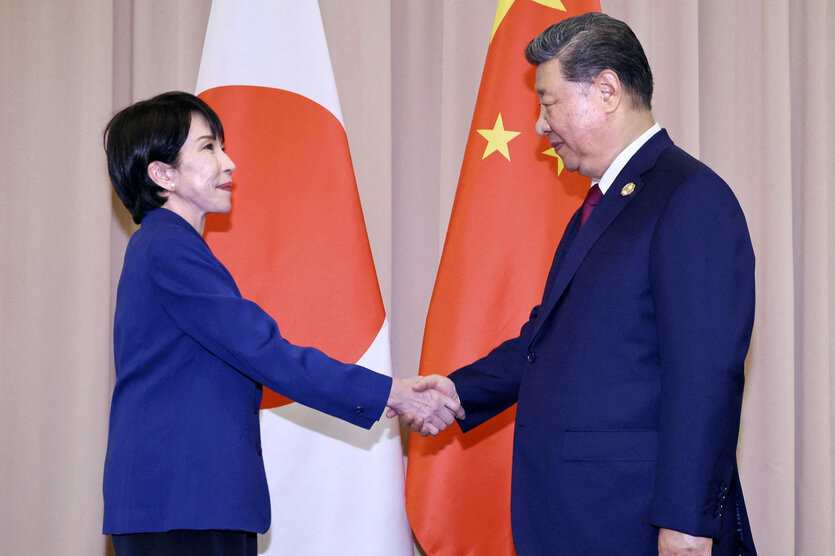 Handschlag zwischen Xi Jinping und Sanae Takaichi vor Nationalfahnen