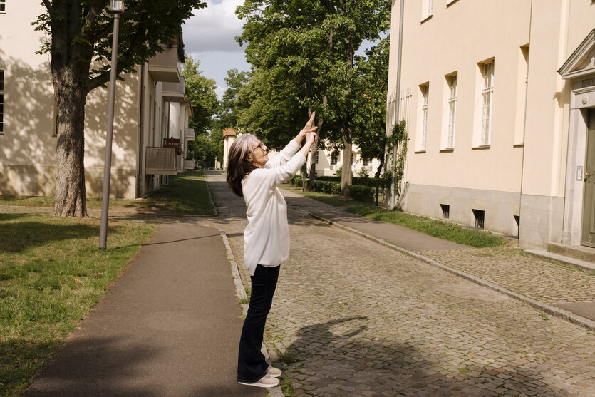 Martina Blankenfeld steht auf dem Gehweg in einer Wohngegend und fotografiert